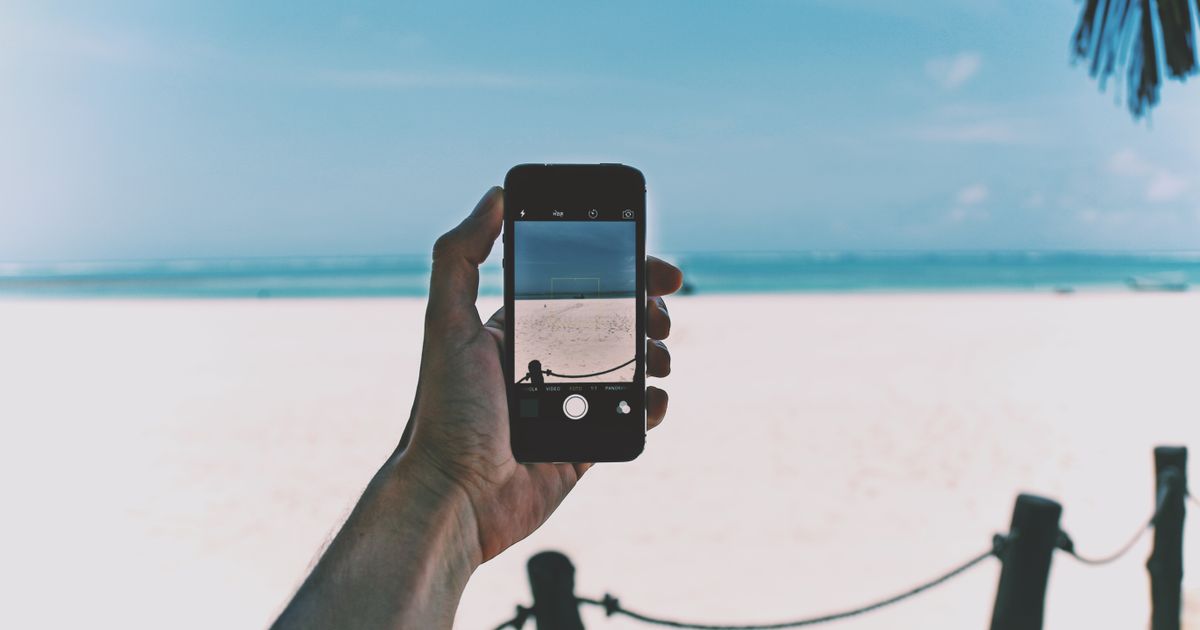 Hand holding a smartphone with a scenic Florida beach view
