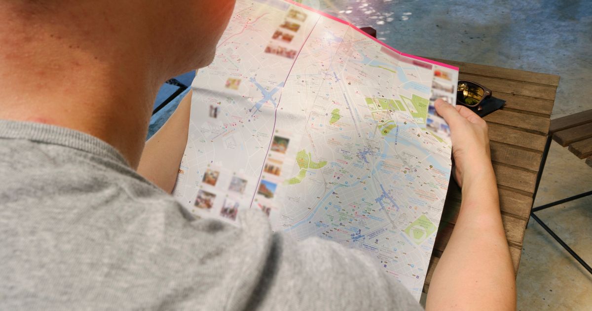Traveller planning a route with a phone and paper map